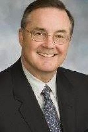 Jason Kelley, Chairman of the Board, is smiling in a suit and tie.