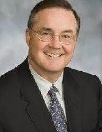 Jason Kelley, Chairman of the Board, is smiling in a suit and tie.