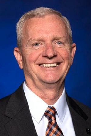 Jason Kelley, Chairman of the Board, smiling in front of a blue background.