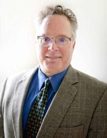 A man in glasses wearing a suit and tie, identified as Jason Kelley, Chairman of the Board.